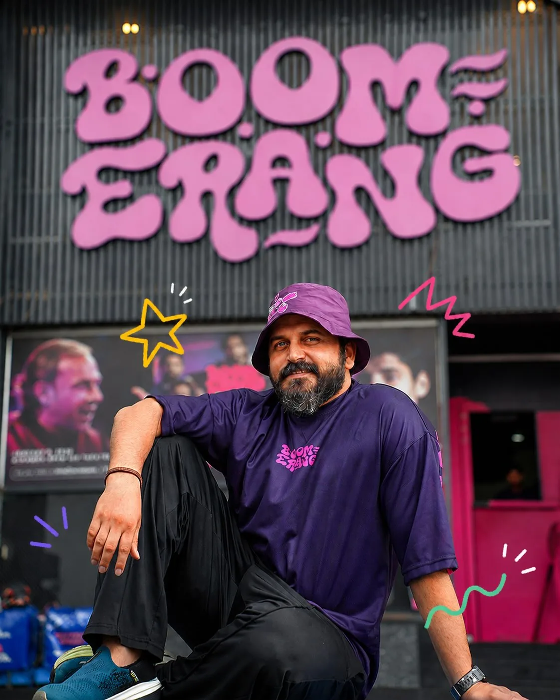 A Boomerang team member in the purple staff tee and bucket hat, seated under the Boomerang sign